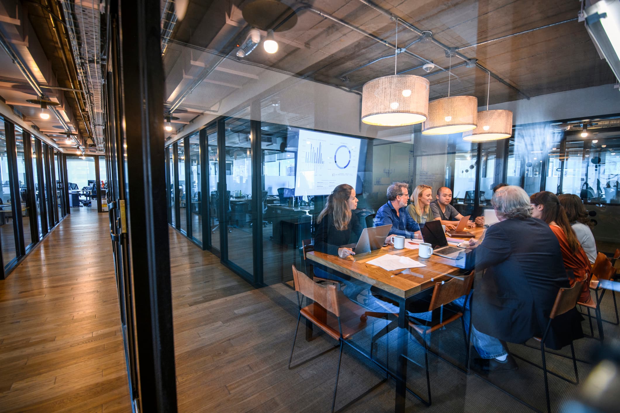 Équipe professionnelle en réunion dans un bureau moderne avec espaces vitrés
